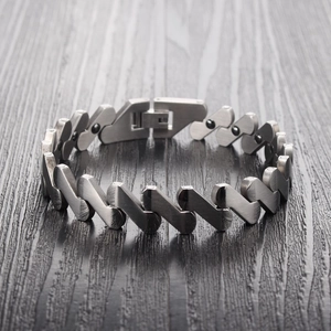 Bracelet magnétique en titane argent mat avec maillons en cœur sur fond de bois sombre