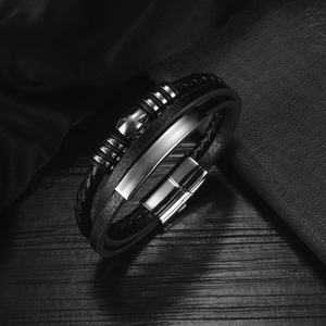 Detail of multi-layer black woven leather bracelet with silver cross and magnetic clasp