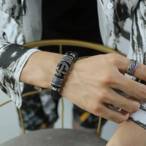 Close-up of vintage multi-layer braided leather bracelet with a silver anchor charm detail