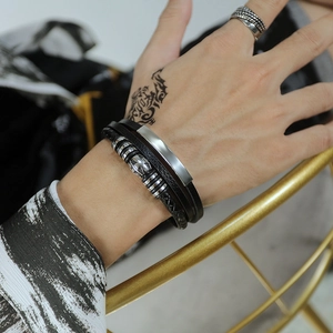 Macro view of multi-layer leather bracelet with cross bead and polished metal bar on wrist