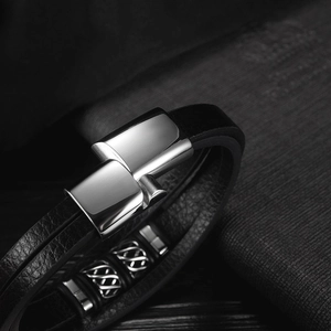 Macro view of multi-layer black leather bracelet with polished steel clasp and Celtic beads