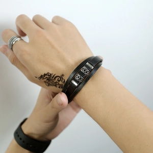 Close-up of multi-layer black leather men's bracelet with silver metal woven textures