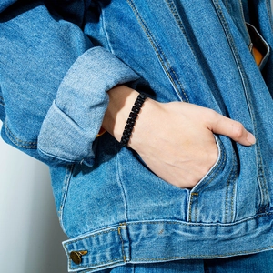 Vue rapprochée d'un bracelet gourmette en acier inoxydable noir mat au poignet masculin