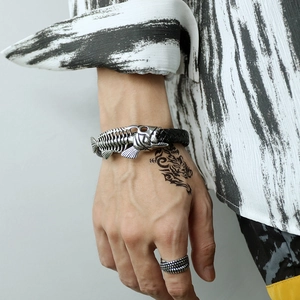 Detail of fish bone stainless steel accessory on black braided leather men's bracelet