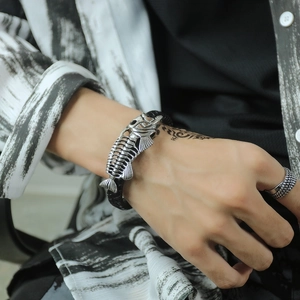 Detail of men's punk fishbone silver bracelet with black braided leather and textured ring