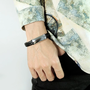 Dettaglio di un bracciale in pelle intrecciata da uomo con placca in acciaio inox lucido