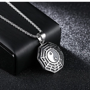Makroansicht von silbernem Tai Chi Bagua Anhänger und quadratischer Gliederkette