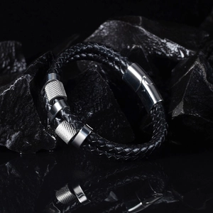 Close-up of double-layer black braided leather bracelet with knurled metal charms