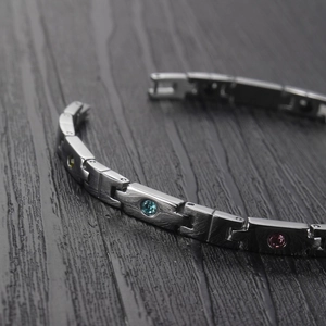 Macro view of titanium steel bracelet featuring colorful zircon stones and brushed metal texture