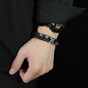 Macro shot of men's double-layer black woven leather bracelet with silver metal X detail