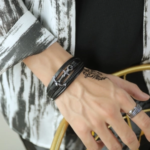 Close-up of men's multi-layer black braided leather bracelet with silver anchor charm