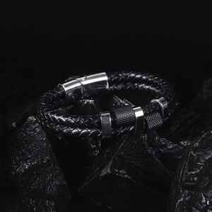 Detail of men's double-layer woven leather bracelet with magnetic steel clasp on dark rock