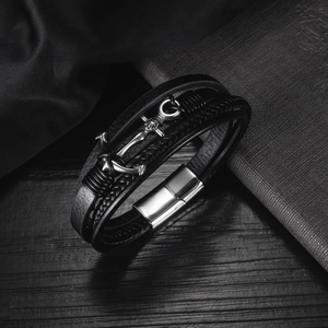 Close-up of a woven leather bracelet with a silver anchor charm and magnetic clasp