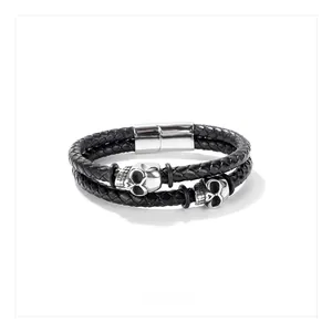 Detail of men's double-layer black braided leather bracelet with skull charms and magnetic clasp