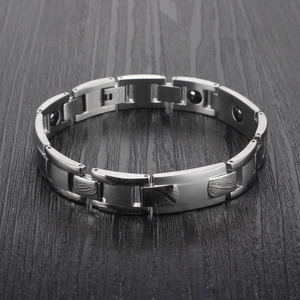 Dettaglio del bracciale magnetico in acciaio inossidabile argento su legno scuro