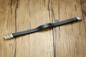 Close-up of black leather bracelet with brushed metal plate and silver buckle