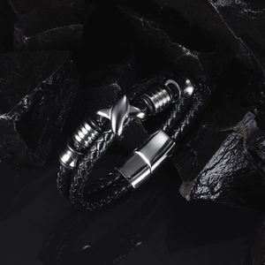 Detail of double-strand braided black leather bracelet with silver cross star charm