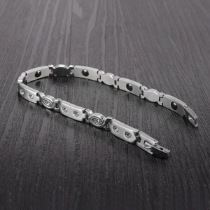 Detail view of magnetic titanium steel bracelet with rhinestones on dark wood background