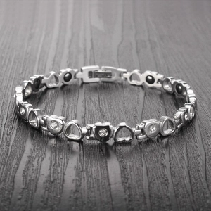 Macro detail of silver heart magnetic health bracelet with zircon inlay and folding clasp