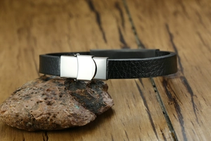 Detail of masculine black leather bracelet with polished steel push-in clasp on stone
