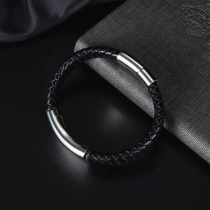 Bracciale da uomo in pelle nera intrecciata con chiusura in acciaio su sfondo scuro
