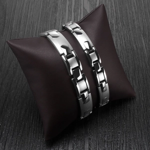 Dettaglio di braccialetti magnetici in argento per coppie su supporto in pelle