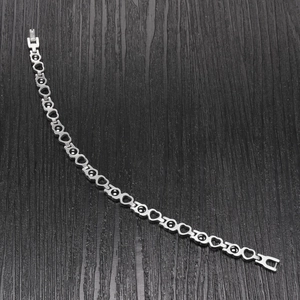 Close-up of silver hollow heart bracelet with magnetic black stones on dark wood background