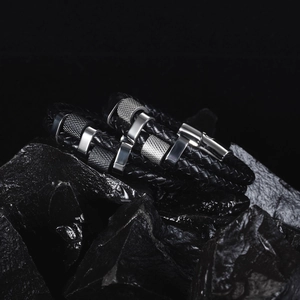 Men's double-layered black braided leather bracelet with silver metal charms on dark stone