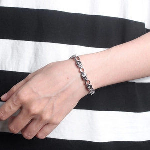Silver heart link bracelet with rhinestones worn by a model on striped background