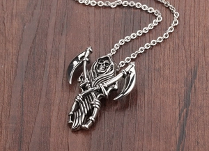 Macro shot of stainless steel grim reaper pendant with double scythe on wood surface