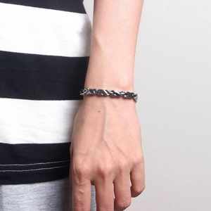 Detailansicht eines silbernen Magnettherapie-Armbands am Handgelenk einer Frau