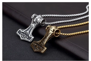 Macro view of gold and silver Mjolnir pendants with Nordic totem carvings on leather
