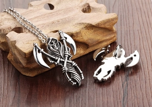 Detailed view of stainless steel grim reaper pendant with scythe on weathered wood