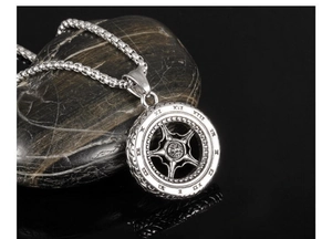 Macro shot of punk style tire-shaped pendant with Roman numerals on a dark stone