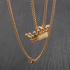 Close-up of golden crown pendant with detailed embossing on a classic box chain necklace
