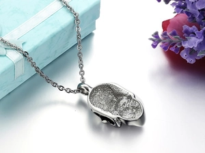 Detail of silver skull pendant with honeycomb textured back on high-gloss white background