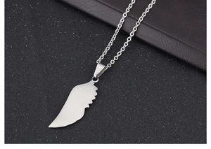 Macro detail of silver angel wing pendant in polished titanium steel with O-chain