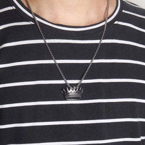 Close-up of hip-hop style silver crown pendant on a chain necklace worn by a model