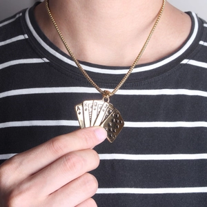 Detail of gold titanium steel poker royal flush pendant necklace worn by a male model