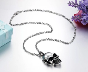 Detailed view of punk 3D skull pendant with thick steel chain on gift box