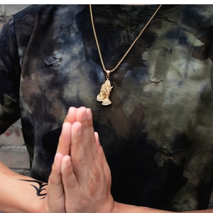 Détail du pendentif mains en prière doré avec strass sur chaîne en acier inoxydable