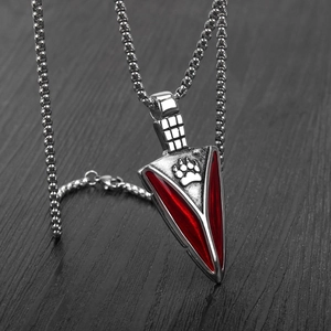 Arrowhead pendant necklace with red enamel and paw print on grey wood background