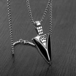Macro shot of silver spearhead pendant with black paw print detail on wooden surface