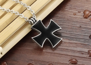 Detail view of a gothic black enamel cross pendant with a silver metallic frame and chain