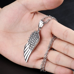 Minimalist silver angel wing feather pendant necklace held by hand for size reference