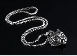 Close-up of realistic tiger head pendant in polished steel with round box chain