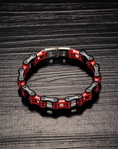 Vue macro d'un bracelet gourmette moto en acier inoxydable rouge et noir sur bois