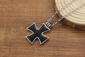 Detailed view of men's iron cross pendant necklace with black enamel inlay on wood background