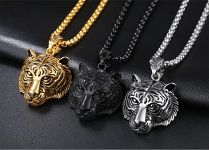 Detailed close-up of tiger head pendants in gold, black, and silver finishes with box chain