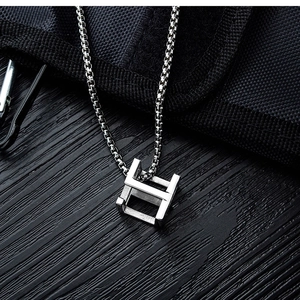 Close-up of industrial silver H-shaped cube pendant on stainless steel chain link